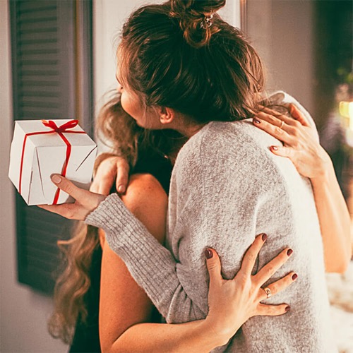 two women exchanging gift hugging
